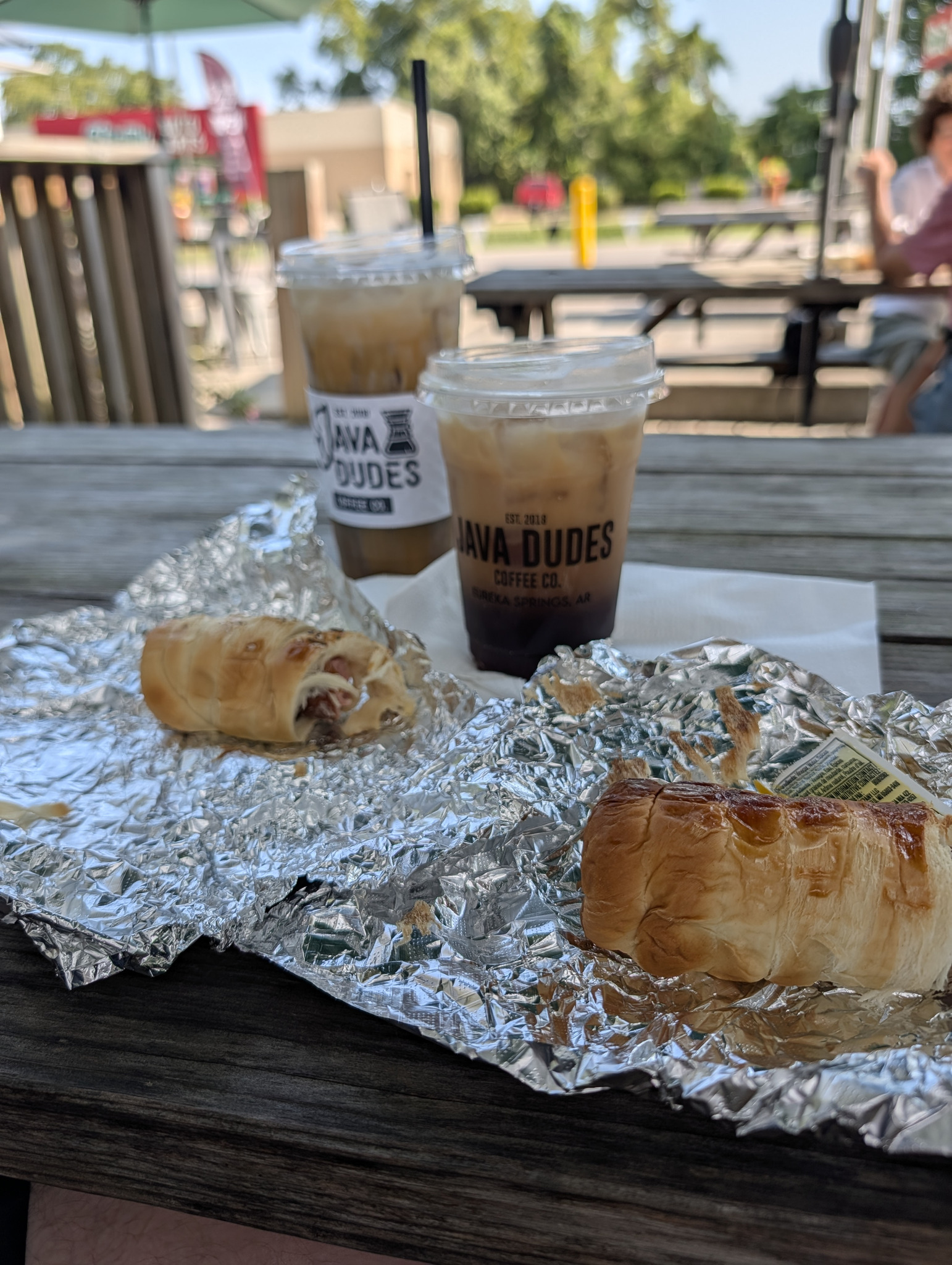 Two iced coffees and two pastries on a picnic table